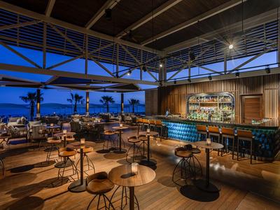 Modernes Hotelrestaurant mit Holzmöbeln und Blick auf den Abendhimmel.