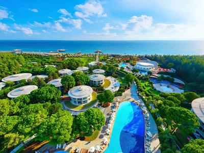 Luftaufnahme eines tropischen Resorts mit runden Gebäuden, Pool und üppiger grüner Umgebung.