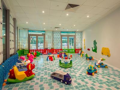 Bunter Spielraum mit weichem Boden, kindgerechten Spielzeugen und bunten Klapptüren am Fenster.