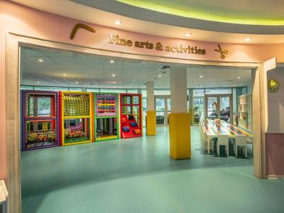 Hell gestalteter Kinderspielbereich mit bunten Regalen und Spielzeug, weichem Boden und großzügigem Raum.