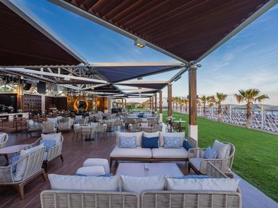 Área exterior moderna de bar de playa con muebles lounge y vista a la playa.