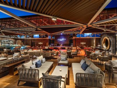 Restaurante moderno y elegante con sillones acogedores y luz cálida bajo un techo de madera.