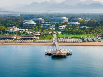 Vista de un complejo costero con un muelle, playa y hoteles al fondo con buen tiempo.