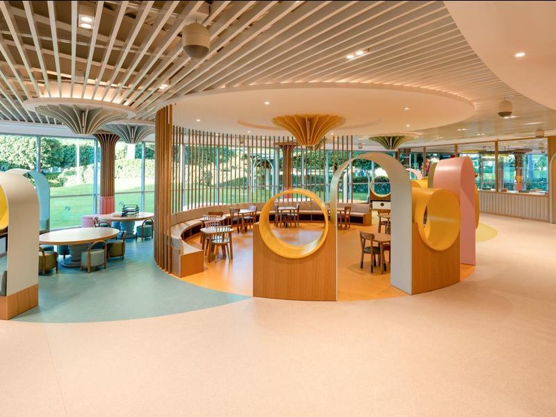 Interior moderno y luminoso con sillas colgantes, grandes ventanales y áreas de descanso acogedoras en un hotel.