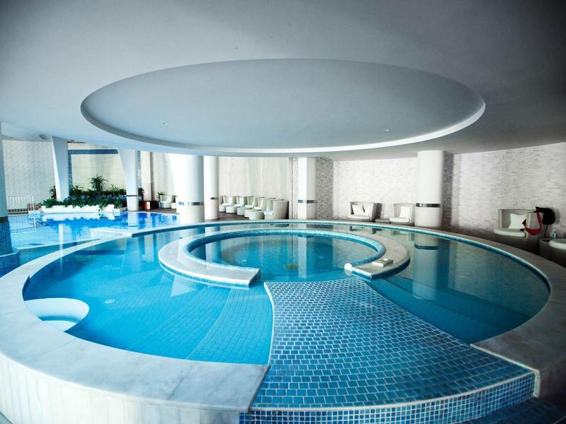 Piscina interior moderna con vaso redondo y elegante iluminación de techo en un hotel.