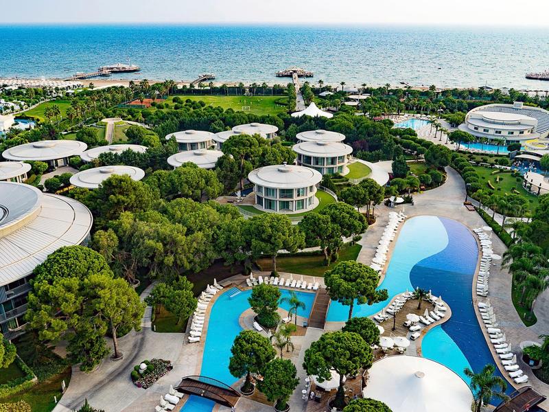 Vista aérea de un resort con piscinas, edificios redondos y vista al mar.