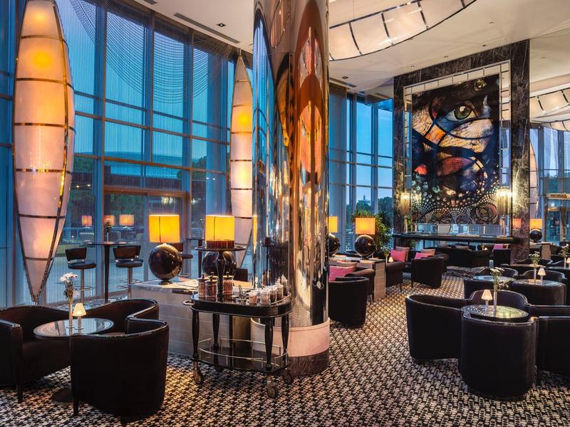 Moderna recepción de hotel con grandes ventanales, iluminación LED y áreas de descanso elegantes.