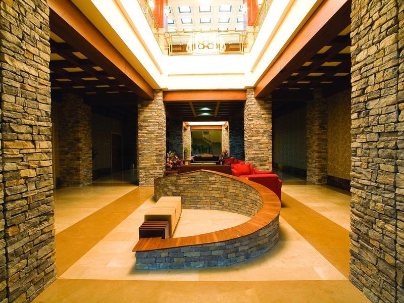 Gezellige hotellobby met stenen muren, houten plafond en gebogen zithoek met kussens.