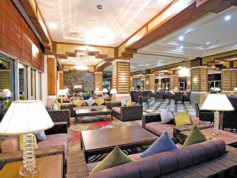 Ruime hotel lounge met moderne zitplaatsen, houten pilaren en zachte verlichting.