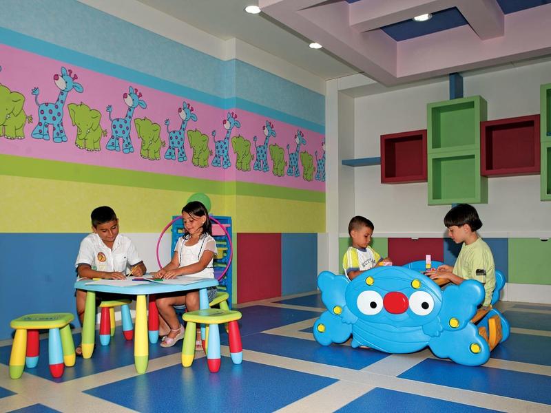 Kinderen spelen en zitten in een kleurrijke indoor speelkamer met felle muren en meubels.