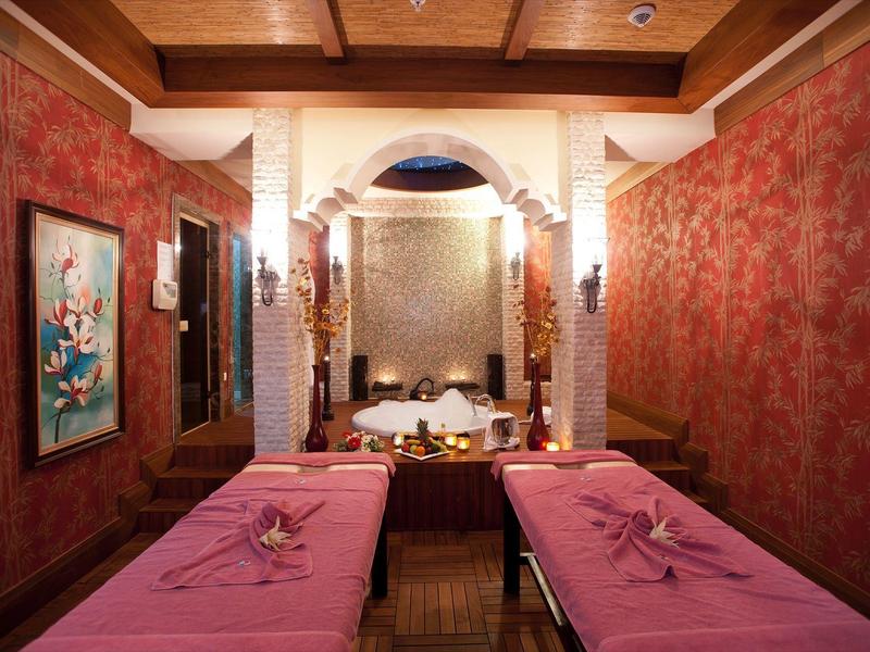 Gezellige spa kamer met twee massagetafels, zachte verlichting en rode muren.