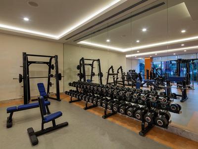 Moderner Fitnessraum mit Hantelregal, verstellbarer Bank und großen Spiegeln an der Wand.