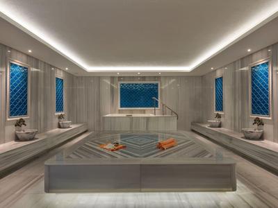 Moderner türkischer Hamam mit grauem Marmor, Spiegeln und blauen Wandfliesen.