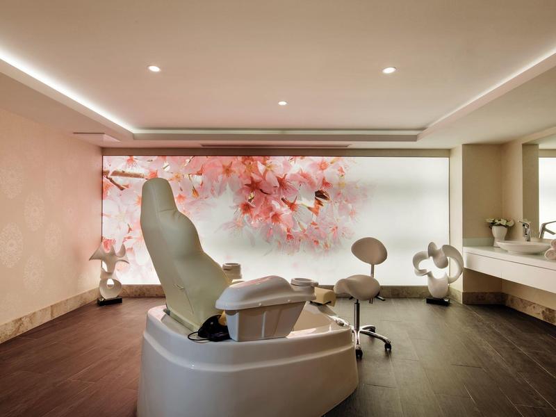 Sala trattamento moderna con sedie comode e grande decorazione murale con fiori di ciliegio.