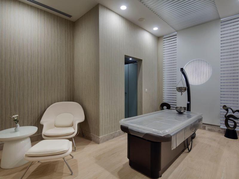 Sala massaggi moderna con poltrone comode e un lettino per trattamenti in tonalità neutre.