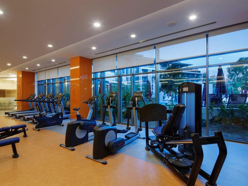 Palestra moderna con attrezzature e grandi finestre che si affacciano su un'area esterna.