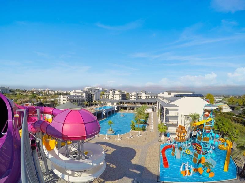 Vista di un parco acquatico con scivoli e piscine in una giornata di sole.