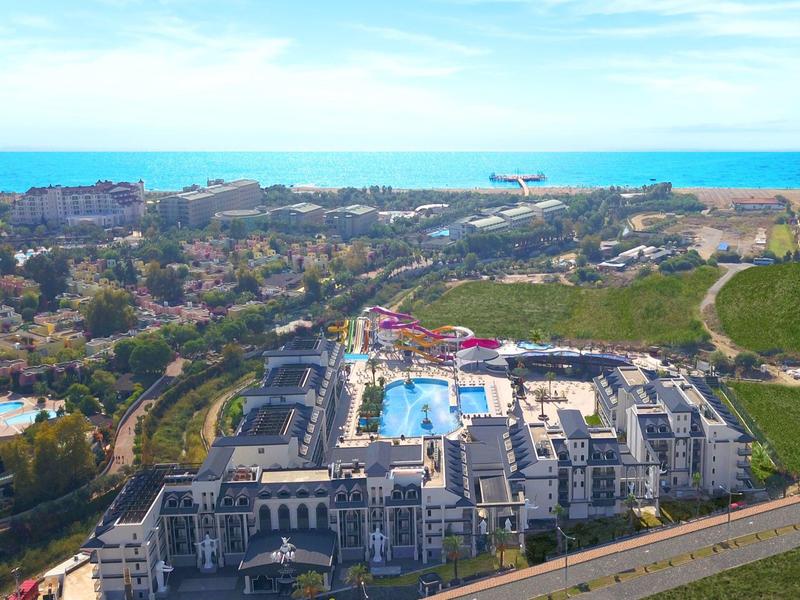 Vista aerea di un grande hotel con piscina in una città costiera con vista sul mare.