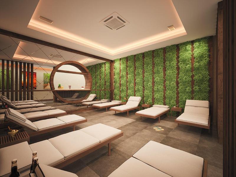 Sala relax moderna con lettini, decorazione murale verde e illuminazione soffusa.