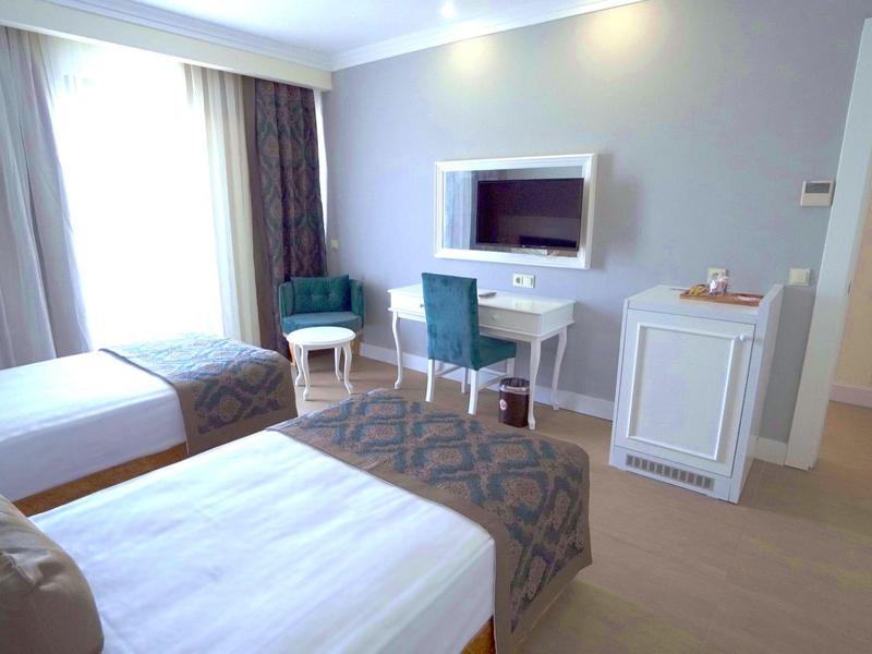 Camera d'hotel con due letti, scrivania, sedie e TV a schermo piatto.