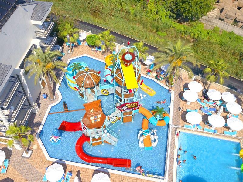Vista aerea di una piscina per bambini con scivoli colorati e giochi accanto a una piscina più grande con lettini.