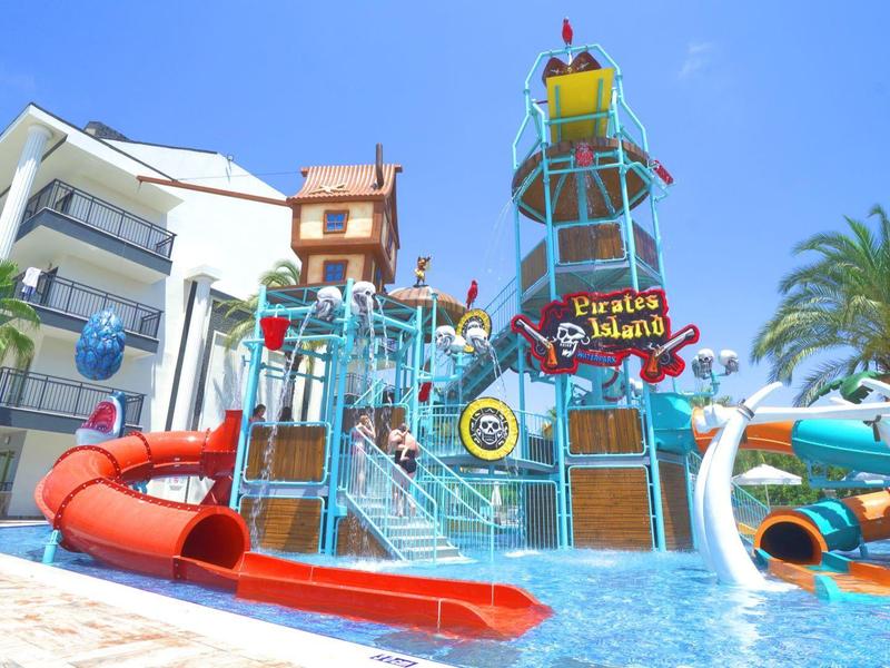 Area giochi acquatica colorata con scivoli e cannoni d'acqua in una piscina dell'hotel con tempo soleggiato.