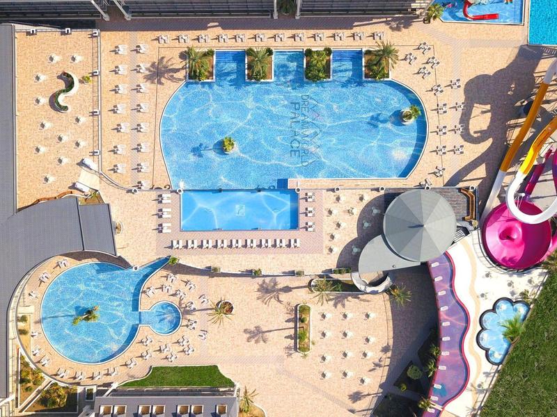 Vista aerea di una piscina dell'hotel con scivoli d'acqua, lettini e terrazze circostanti.