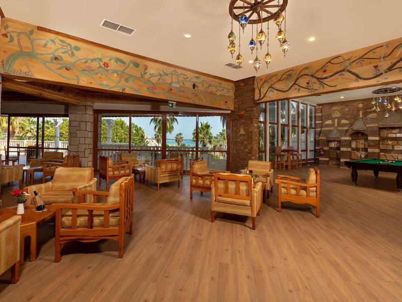 Lichte, ruime hotel-lounge met houten meubels, panoramische ramen en gezellige sfeer.