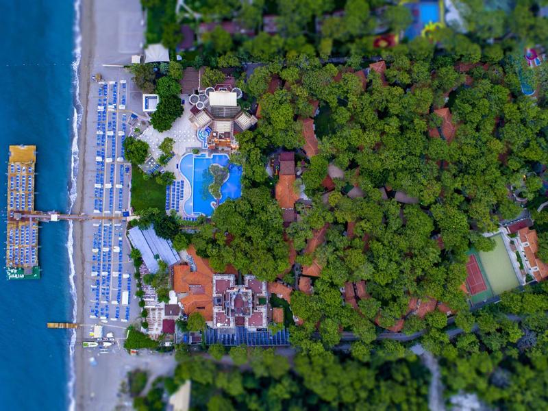 Aerial view of a resort with pool, beach, and dense forested area
