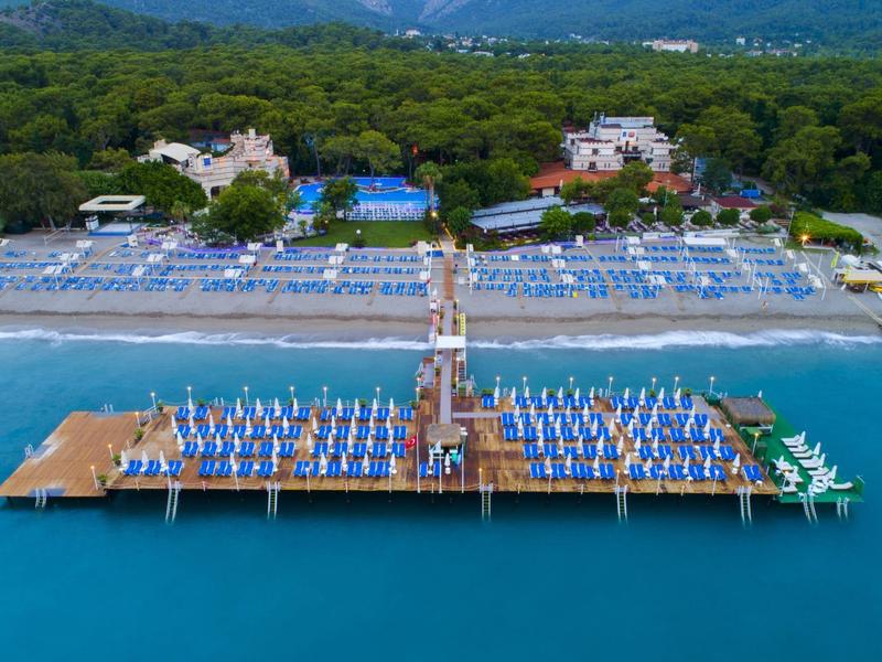 Beach hotel with wooden pier and umbrellas over turquoise sea