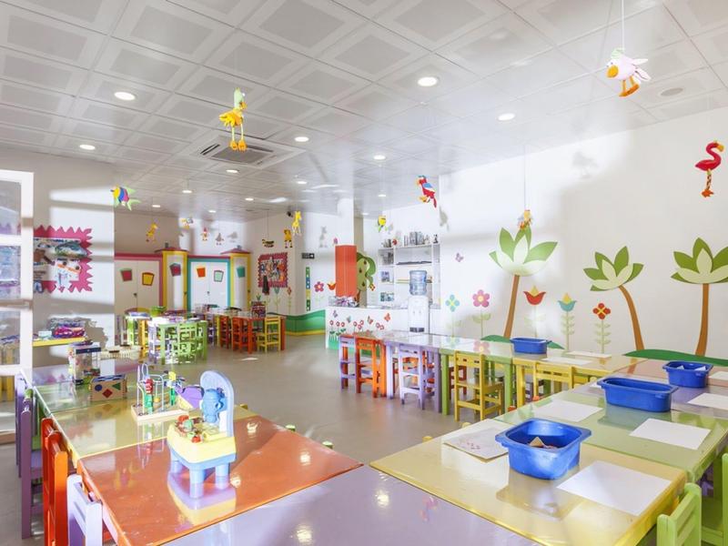 Bright, colorful children's playroom with tables, chairs, and wall decorations in a hotel.