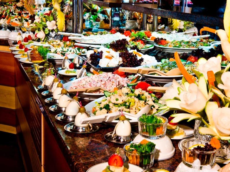 Buffet with diverse dishes and decorative floral arrangements on a countertop