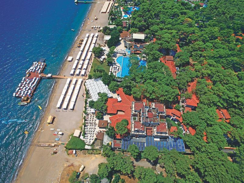 Aerial view of a beach resort with swimming pools, green vegetation, and piers on the water