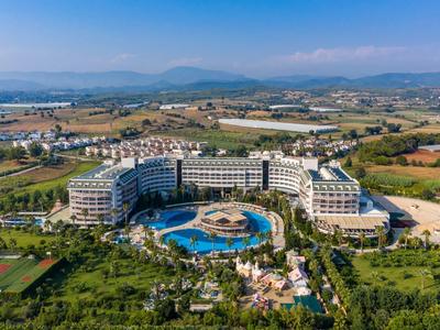 Duży ośrodek hotelowy z basenem na obszarze wiejskim, z górami w tle.