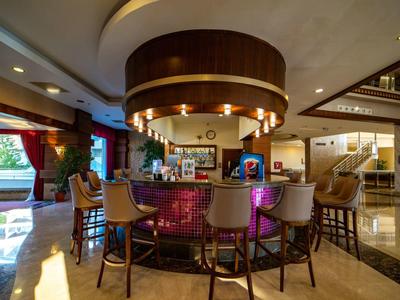 Nowoczesny bar hotelowy z okrągłym kontuarem i wysokimi stołkami w eleganckim otoczeniu.