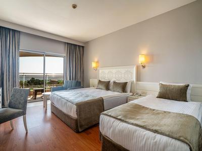 Nowoczesny pokój hotelowy z dwoma łóżkami, krzesłem i balkonem z widokiem na morze.