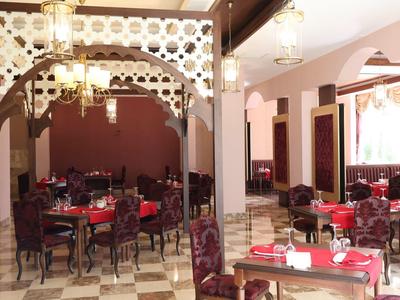 Jasna jadalnia z czerwonymi obrusami i drewnianymi rzeźbionymi meblami w ciepłej atmosferze.