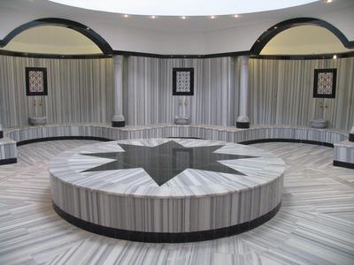 Okrągły marmurowy stół z wzorem gwiazdy w luksusowym, okrągłym pomieszczeniu z ławkami.