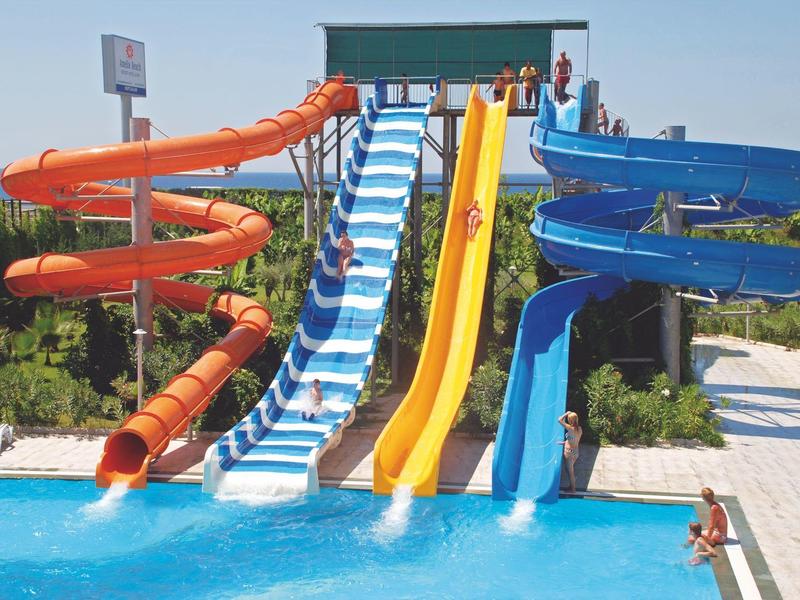 Park wodny z wieloma kolorowymi zjeżdżalniami prowadzącymi do basenu.