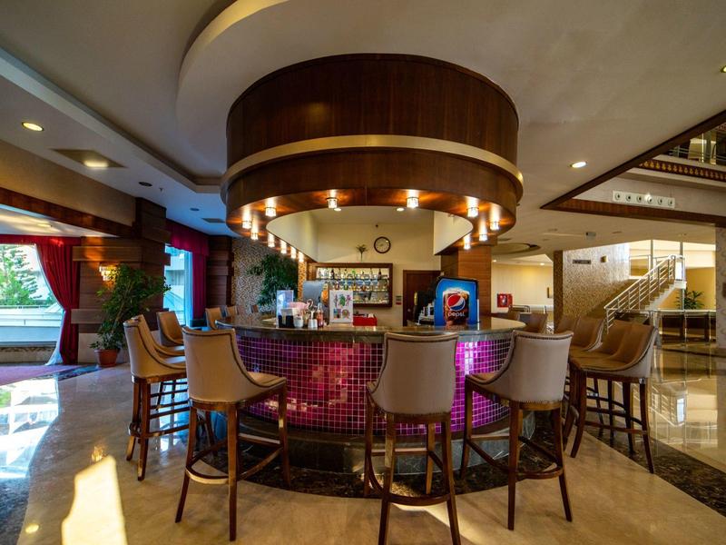 Nowoczesny bar hotelowy z okrągłym kontuarem i wysokimi stołkami w eleganckim otoczeniu.