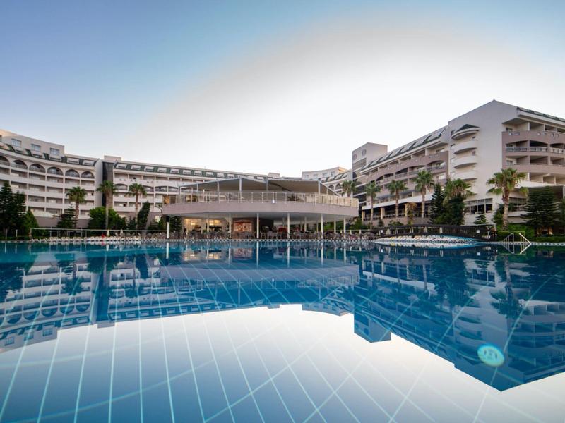 Nowoczesny kompleks hotelowy z dużym basenem na zewnątrz i wieloma piętrami o zmierzchu przy czystym niebie.