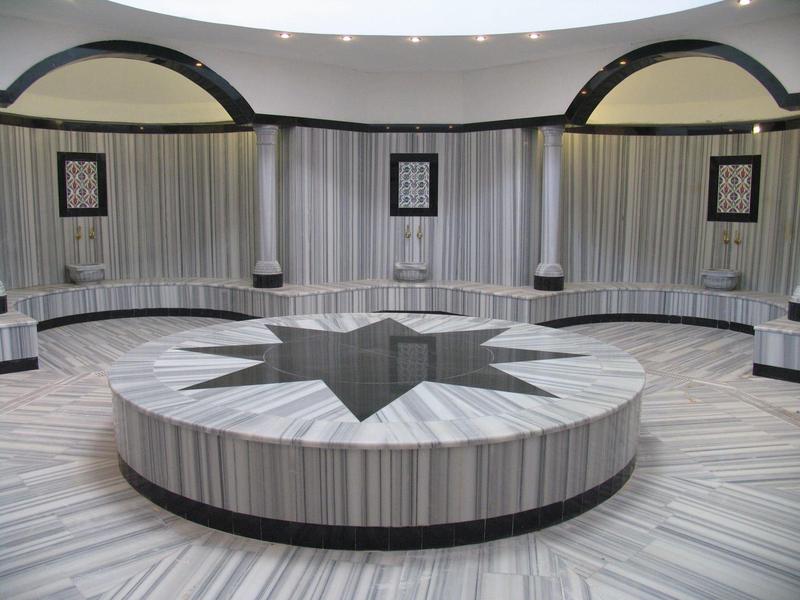 Okrągły marmurowy stół z wzorem gwiazdy w luksusowym, okrągłym pomieszczeniu z ławkami.