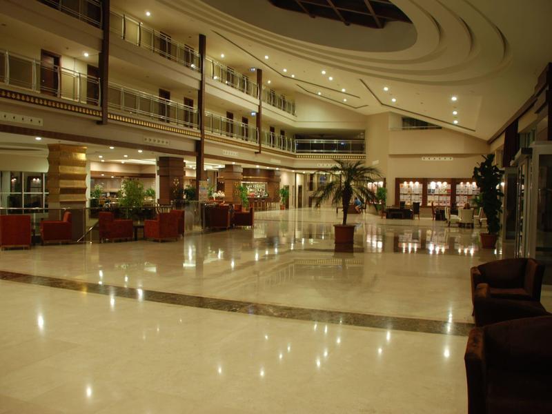 Duża lobby hotelowa z błyszczącą marmurową podłogą i miejscami do siedzenia