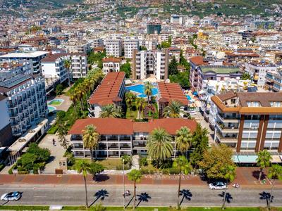Vue sur une zone urbaine avec des immeubles résidentiels et un complexe hôtelier central avec piscine.