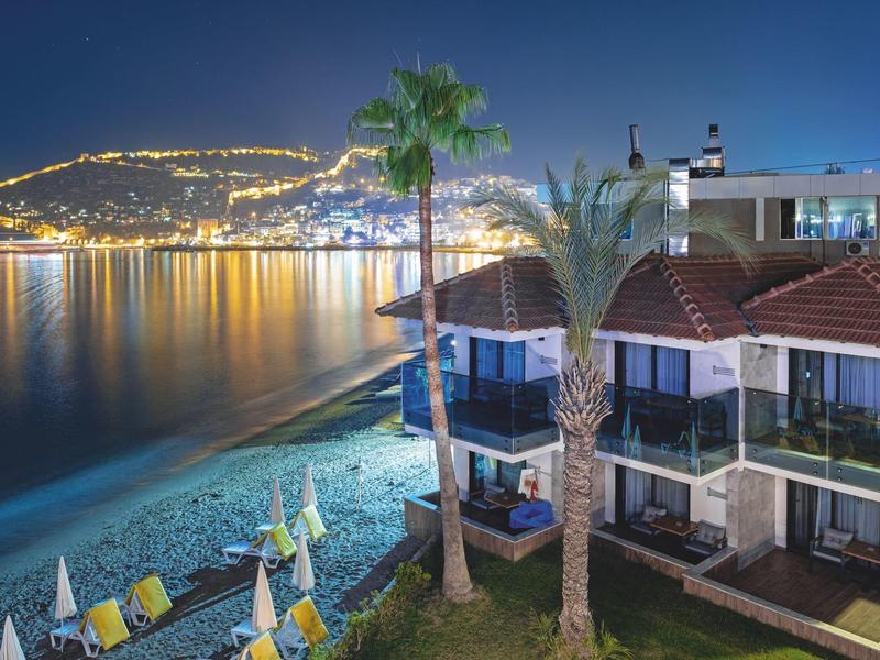 Hôtel en bord de mer la nuit avec côte illuminée et eau calme
