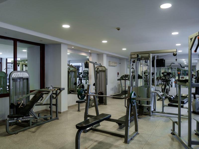 Une salle de sport moderne avec divers équipements d'entraînement et des miroirs au mur.