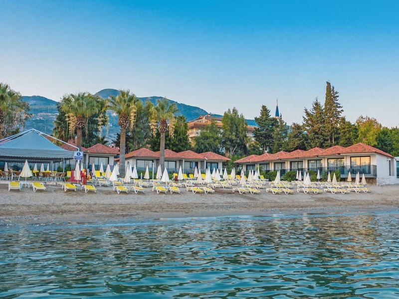 Plage avec transats devant un complexe hôtelier et des palmiers sous un ciel clair