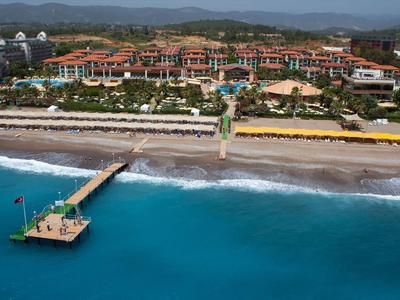 Resort s pláží, bazénem a molem u tyrkysového moře s horským pozadím