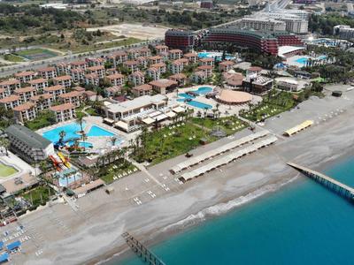 Letecký pohled na resort s několika bazény, pláží a molem u tyrkysového moře.