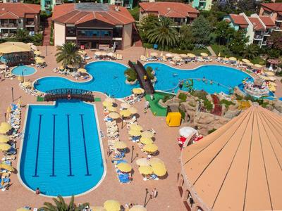 Prostorná venkovní plocha se dvěma bazény, lehátky a slunečníky v hotelovém rezortu.